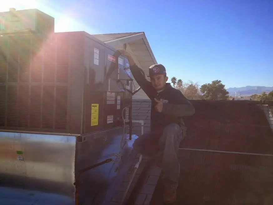 HVAC technician performing Air Duct Repair on a rooftop unit in Bloomington